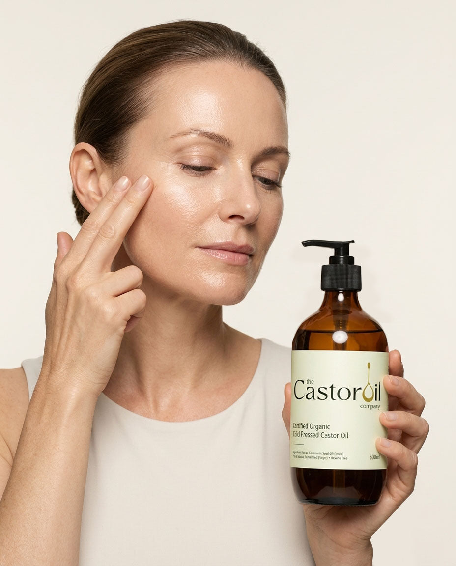 Cold-pressed castor oil being pressed into damp skin on the face after cleansing