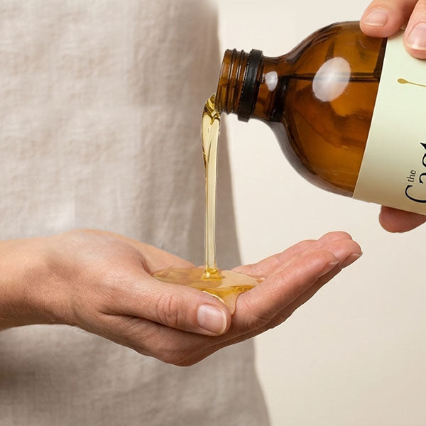 Hexane-free organic castor oil poured from the bottle into a cupped palm